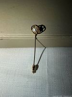 Full view of stick pin upright showing faux pearl cage top and clutch