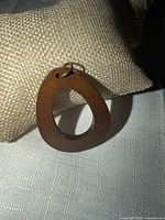 Front view of wooden teardrop pendant on fabric background