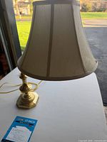 Full view of brass lamp with shade, cord visible