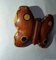 Front view of wooden butterfly brooch showing painted yellow and black spots