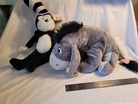 Cat in the Hat and Eeyore plush displayed with ruler for scale