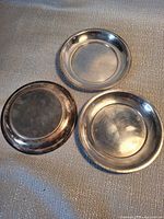 Three round shallow silver-tone dishes front and back