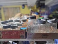 Two boxes containing assorted glass canning jars with metal lids