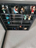 Front view of open black wood shadow box with miniatures in compartments
