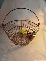Full view of basket with handle raised and faux fruit inside