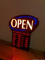 Sign powered on showing illuminated OPEN text and LED business hours display