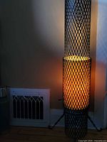 Full view of lit floor lamp against wall