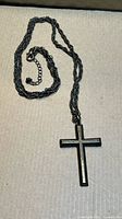 Full view of cross pendant attached to rope chain with extender and clasp