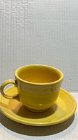 Front view of yellow Fiesta cup on matching saucer