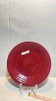 Front view of cinnabar red 9" Fiesta buffet plate on stand