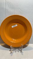 Front view of 9-inch Tangerine Fiesta pasta bowl on stand