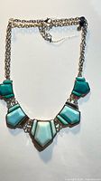 Full view of necklace showing chain, clasp, and geometric turquoise panels