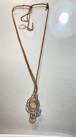 Full view of brown suede rope necklace with wire-wrapped glass orb pendant