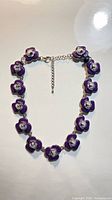 Full view of necklace laid flat showing all lavender enamel rose links