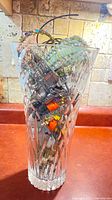 Full view of cut crystal vase filled with assorted jewelry
