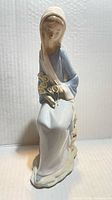 Front view of seated porcelain woman holding lilies