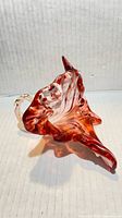 Oblique view of freeform Murano glass flower showing clear handle and red swirl petals