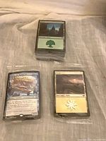 Three sealed bundles of Magic cards, Forest, Charix, and Plains visible