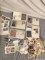 Group of loose stamps, First Day Covers, and envelopes spread on surface