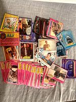 Scattered lot showing mixture of pink Grease, blue Jaws, Superman, Battlestar, ALF cards
