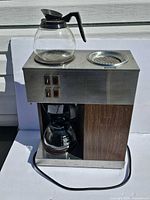 Front view of coffee brewer with one carafe on top warmer and one below brew basket