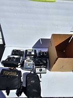 Group shot of six vintage Kodak cameras, two bags, cardboard box