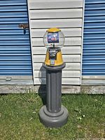 Full view of gumball machine on pedestal outdoors