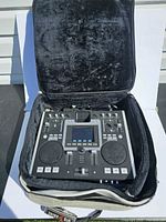 Numark iDJ2 mixer seated inside black plush-lined grey soft carrying case with strap visible