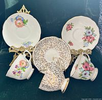 Three cup and saucer sets displayed; shows patterns and condition