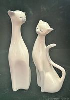 Front view of both long-neck Siamese cat figurines