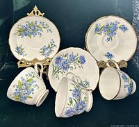 Three teacup and saucer sets displayed to show patterns and gold trim