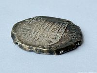 Obverse view of the 4 Reales silver cob showing shield design and irregular edges