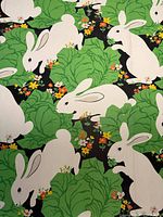 Close-up of wallpaper pattern showing white rabbits, green leaves, orange and yellow flowers on black background