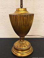 Full view of lamp base and body showing gilt finish, fluted design, central rod