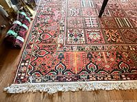 Full view of rug corner showing pattern, fringe, rolled extra textile nearby