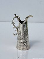 side profile of silver jug showing cherub repoussé motif and handle