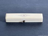 Top view of closed rectangular carved case showing rose gold inlay motif and clasp