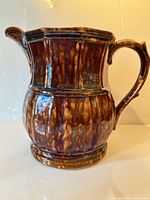 Full view of brown and blue mottled pottery pitcher showing form and handle