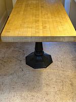 Full view of rectangular pine top and black cast iron pedestal base
