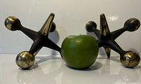 Pair of bronze jacks front view with apple for scale
