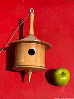 Front view of turned wooden birdhouse with apple for scale