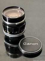 Lens standing upright with front cap beside it, showing exterior condition and included cap
