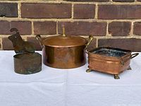 Three copper items: lidded pot, animal-handle container, footed planter