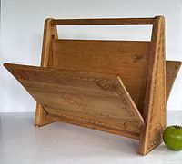 Overall view of wooden magazine rack showing handle and carved sides