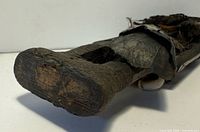 Close-up of base and lower section of carved wooden fertility doll with cloth skirt