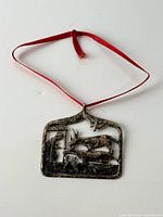 Front view of sterling silver ornament with red ribbon