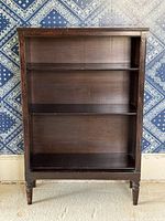 Front view of wood bookcase showing three shelves and tapered legs