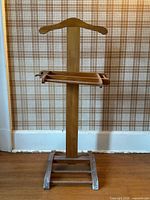 Full view of wooden valet stand showing hanger top, tray, trouser bar, shoe rack base