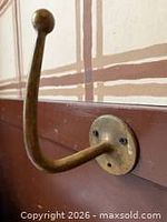 Side view of brass hat hook showing curved arm and mounting plate