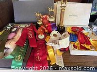 Assorted ribbons in two boxes with three horse trophies